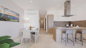 Una cocina moderna con una isla central, muebles blancos y vista al comedor.