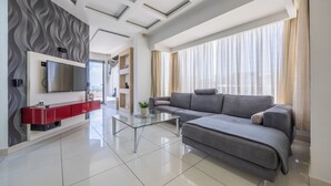 A modern living room with a grey sofa, a glass coffee table, and a flat-screen TV mounted on a wall with a wavy pattern. - For those who prefer to cook their own meals, this kitchen is well-equipped and is a beautiful space to create heartly dishes!! <br>Towels and linen are included, Kettle, Toaster, Hair dryer, Washing machine, coffee maker, dishwasher, microwave. (Il-Mellieħa)