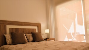 A hotel room with a large bed, a wooden headboard, and a nightstand with a lamp.