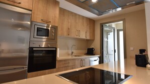 A modern kitchen with stainless steel appliances, wooden cabinets, and a glass cooktop.