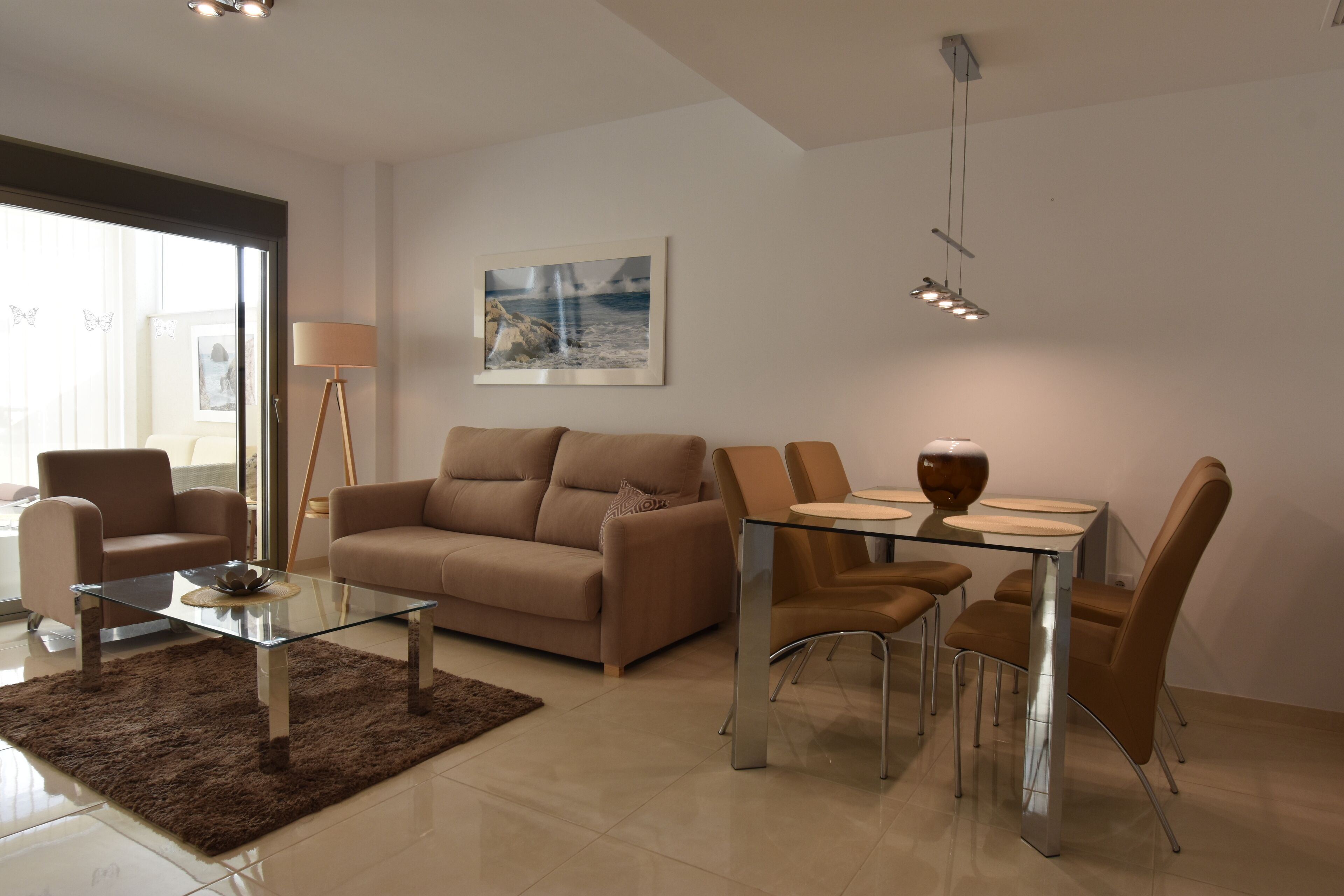 En moderne stue med et glasbord, beige sofaer, et spisebord med stole og et maleri på væggen.