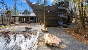 Eine moderne Hütte mit einer markanten Wendeltreppe und einer überdachten Veranda.