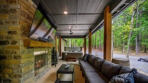 Ein gemütliches Wohnzimmer mit Kamin aus Stein, einer großen Couch und einem flachbildfernseher an der Wand.