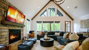 Ein geräumiges Wohnzimmer mit Kamin, einem großen, an einer Steinwand befestigten Fernseher und einer modernen Sofagarnitur.