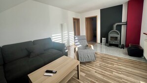 A modern living room with a grey sofa, a wooden coffee table, and a fireplace. - Ferienwohnung im Grünen (Hainichen)
