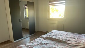 A bedroom with a bed, a wardrobe, a window, and a radiator. - Ferienwohnung im Grünen (Hainichen)