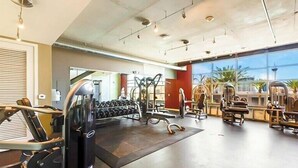 Un gimnàs amb diversos equips d'exercici, incloent cintes de córrer, peses i aparells de musculació.