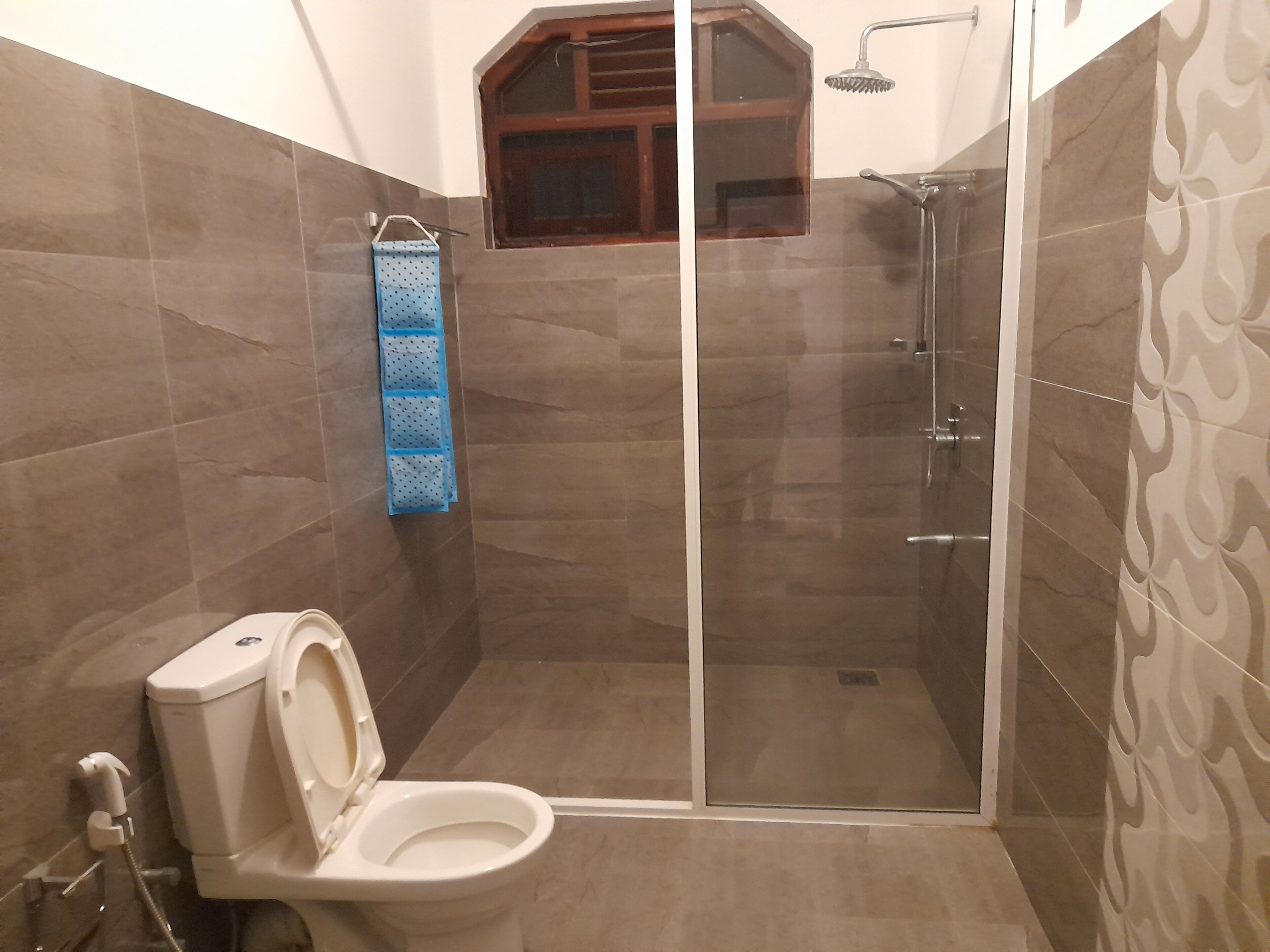 A bathroom with a toilet, a shower, and a towel rack.