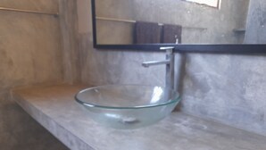A bathroom with a glass bowl sink, a mirror, and a towel rack. - Mealanies House (Unawatuna)