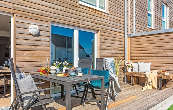 Ein Essbereich im Freien mit Tisch, Stühlen und Blick auf das Haus.