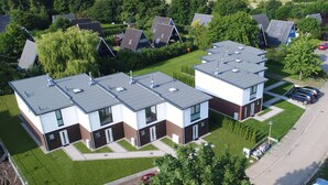 A modern residential building with multiple units, each featuring a flat roof and large windows. - Baltic Village - Comforthaus (Damp)