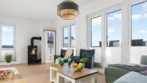 A modern living room with a fireplace, large windows, and a cozy seating area. - Lovely apartment in Olpenitz with sauna (Olpenitz)