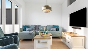 A modern living room with a sofa, a coffee table, a TV, and a cabinet. - Lovely apartment in Olpenitz with sauna (Olpenitz)
