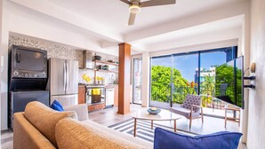 A modern living room with a sofa, a coffee table, and a balcony with outdoor furniture. - Casita Layla (Puerto Vallarta)