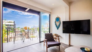 A modern living room with a large sliding glass door leading to a balcony with a city view. - Casita Layla (Puerto Vallarta)