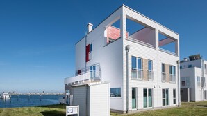 A modern two-story building with a flat roof, large windows, and a balcony.