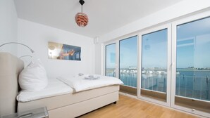 A modern bedroom with a large window, a bed, a bedside table, and a unique pendant light.