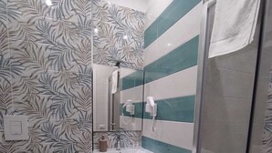 Ein Badezimmer mit Toilette, Waschbecken mit Spiegel und Duschbereich.