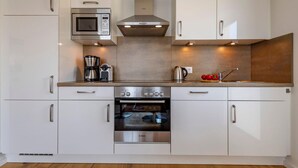 Une cuisine moderne avec des meubles blancs, un four à micro-ondes de marque Bosch, une machine à café et un four traditionnel.