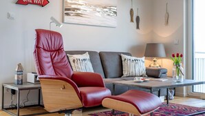Un salon moderne avec un fauteuil en cuir rouge, un canapé gris et une table basse.