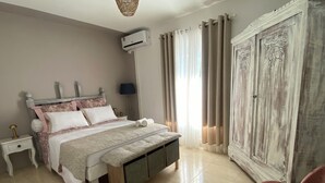 A bedroom with a bed, bedside tables, a wardrobe, and a chair. - Mzelle Pipine à 2 Minutes de la Plage ! (Saint-Pierre)
