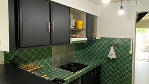 A kitchen with black cabinets, green tiles, and a gas stove. - Mzelle Pipine à 2 Minutes de la Plage ! (Saint-Pierre)