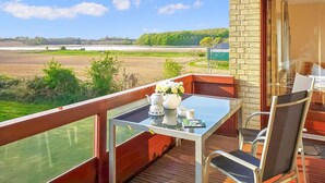 A balcony with a table set for tea, overlooking a field and a body of water. - Cozy apartment in Boren with sauna (Boren)
