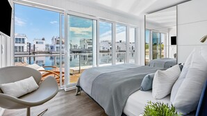 Una camera da letto moderna con un ampio letto, una sedia e vista su un porto turistico.
