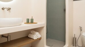 A modern bathroom with a freestanding bathtub, a sink with a mirror, and a shower area. - BLUE SEA NAXOS  (Naxos)