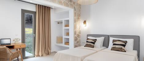 Un dormitorio moderno con dos camas, un escritorio con una computadora portátil, una silla de mimbre y una pared de piedra.
