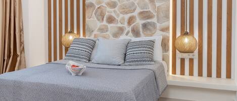 Ein Schlafzimmer mit einer Steinwand, einem Bett mit gemusterten Kissen und zwei Pendelleuchten.