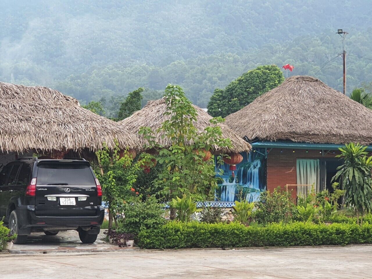 A black SUV parked in front of a building with thatched roofs and a waterfall mural.