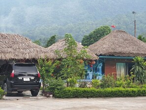 A black SUV parked in front of a building with thatched roofs and a waterfall mural.