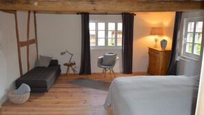 Un dormitorio con cama, sofá cama, sillón, lámpara y armario.