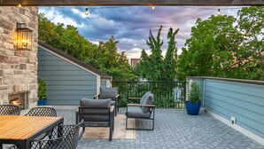 A patio with outdoor furniture, a stone wall, and a view of trees and buildings. - Rooftop Relaxation in Downtown Murfreesboro (Murfreesboro)