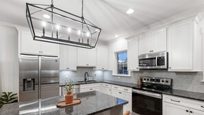 A modern kitchen with white cabinets, stainless steel appliances, and a granite countertop. - Rooftop Relaxation in Downtown Murfreesboro (Murfreesboro)