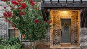 A brick building with a dark green door, a number '103' above the door, and a wreath on the door. - Rooftop Relaxation in Downtown Murfreesboro (Murfreesboro)