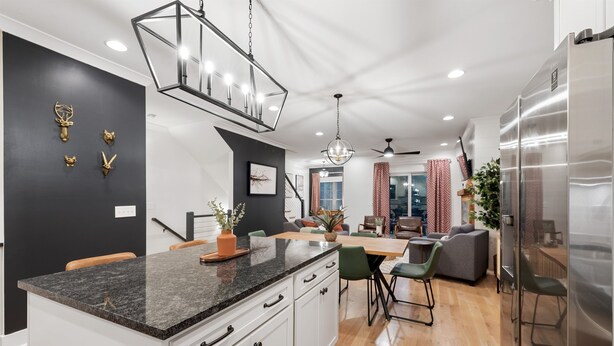A modern kitchen with a granite countertop, white cabinets, and a stainless steel refrigerator. - Rooftop Relaxation in Downtown Murfreesboro (Murfreesboro)