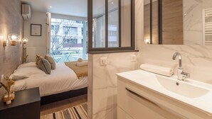 Un dormitorio moderno con una cama grande, mesita de noche con un jarrón y vistas al exterior.