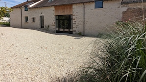 A rustic stone building with a gravel driveway and a large sliding glass door. - Family-Friendly Getaway: Heated Pool, Garden, Near Fontainebleau & Paris (Aulnay-la-Rivière)
