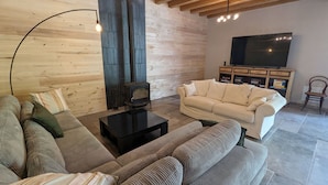 A living room with a sofa, a coffee table, a TV, and a fireplace. - Family-Friendly Getaway: Heated Pool, Garden, Near Fontainebleau & Paris (Aulnay-la-Rivière)