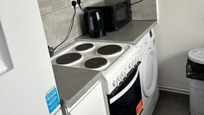 A compact kitchen with a stove, microwave, and washing machine.