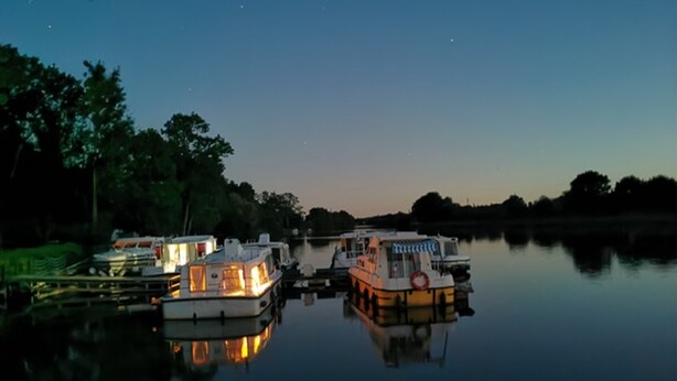 A calm river at dusk with several boats docked.