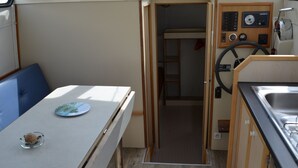 A compact kitchenette with a stove, sink, and a small dining area with a table and chairs. - Exclusive Stay on Triton 860 Fly (Pontailler-sur-Saône)