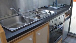 A kitchen with a stainless steel sink, a gas stove, and a built-in oven. - Exclusive Stay on Triton 860 Fly (Pontailler-sur-Saône)