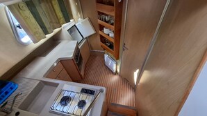 A compact RV kitchen with a stove, sink, and storage shelves. - Journey on Iris - Houseboat for 5 guests (Chenillé-Changé)