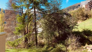 Un paysage montagneux avec un bâtiment entouré d’arbres.