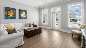 A spacious living room with a white sofa, a wooden coffee table, and two paintings on the wall.