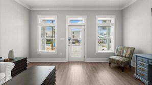 A spacious room with a large window, a door, and a chair.
