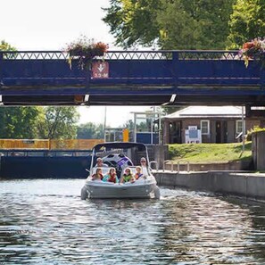 Een boot met passagiers op een gracht onder een brug.